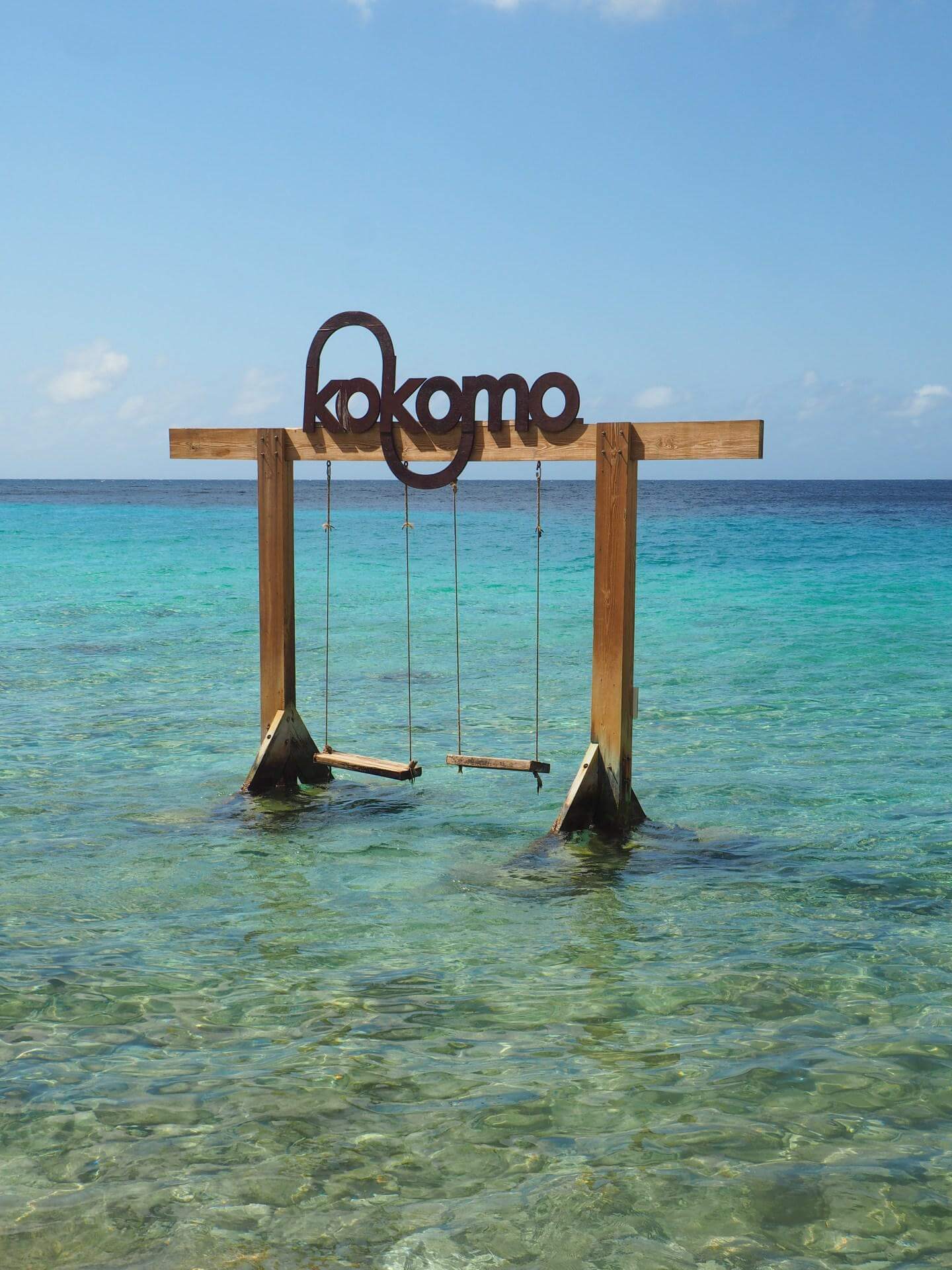 Kokomo Beach Swing over clear turquoise waters with a wooden frame in the shallow ocean, offering a scenic view at Kokomo Beach.