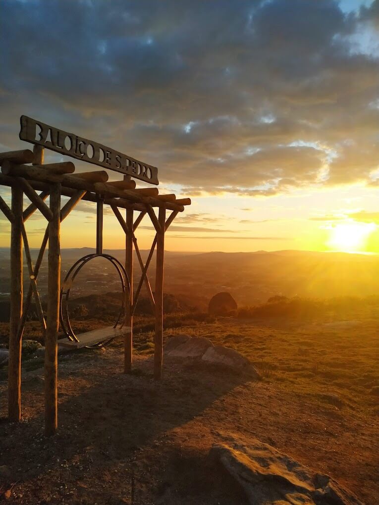 Image shows the São Pedro Fins swing at sunset, with a golden sky and scenic landscape in the background.