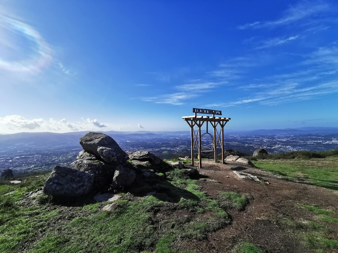 The São Pedro Fins swing is pictured with its surroundings under a clear blue sky, overlooking a vast valley and rocky terrain.