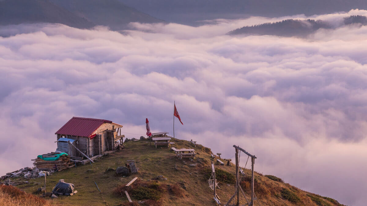 A small cabin, a Turkish flag, a hammock, a bench seat, and most importantly, a swing overlooking a sea of clouds on a mountain peak.